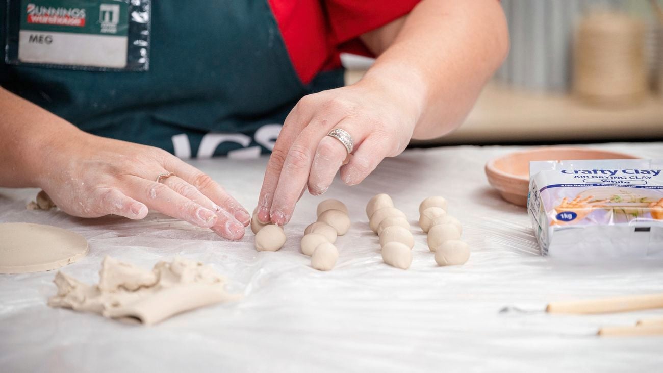 A bunnings team member rolling out small balls.