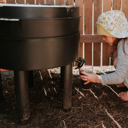 A child collecting leachate from the bottom of a compost bin