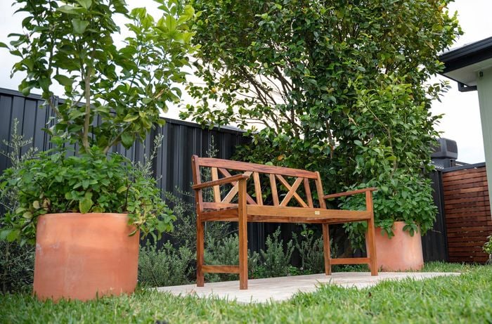 A garden with a wooden bench and two plant pots.