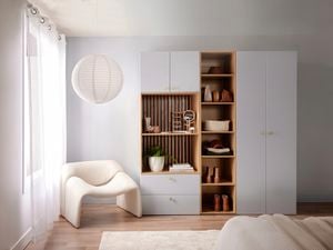 White storage cabinet in a bedroom with a white chair and a bed in it.