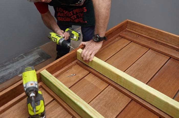Person drilling pieces of wooden table together.