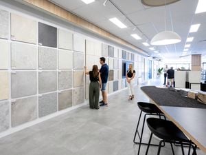 Customers browsing a showroom wall of large tile samples arranged in a grid.
