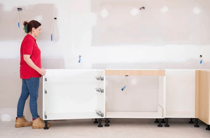 A Bunnings Team Member is positioning base cabinets in place to check layout, spacing, and fit during a kitchen installation.