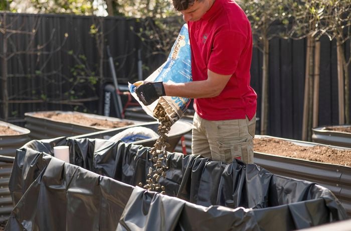 A Bunnings Team Member is adding the drainage gravel to the garden bed.