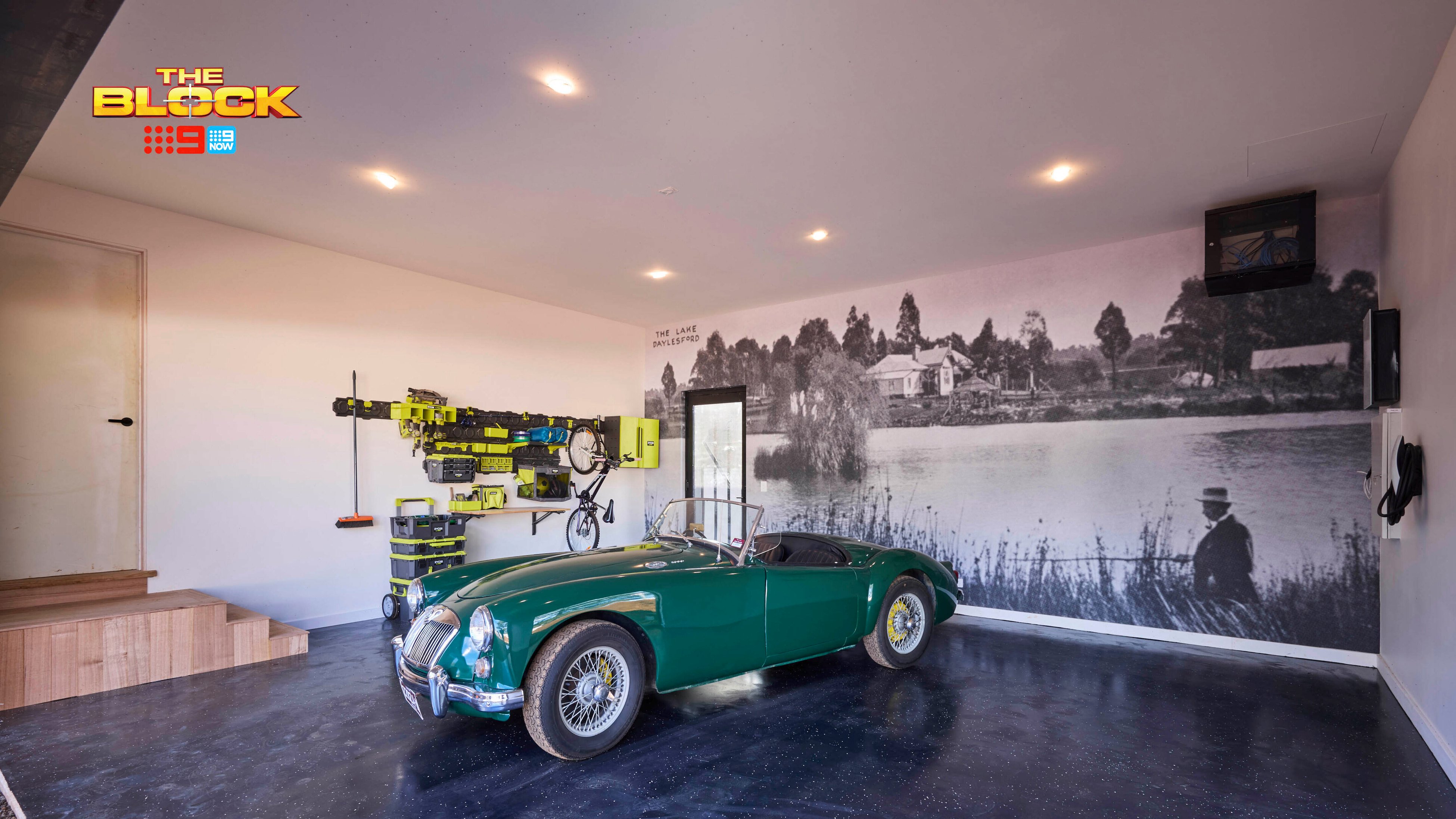 Modern garage from The Block featuring a green vintage car, wall mural, tool storage, and polished dark flooring.