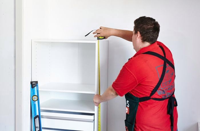 Person measuring height of wardrobe insert unit shelving.