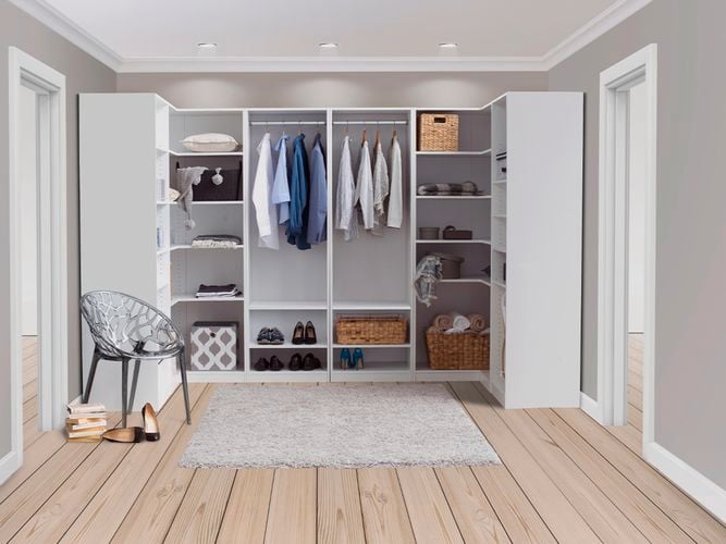 A walk in wardrobe with clothes and shoes in it with a chair in front of it