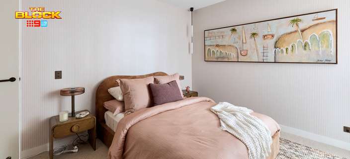 Contemporary bedroom featuring soft pink bedding, a curved timber bedhead, bedside table and framed artwork.