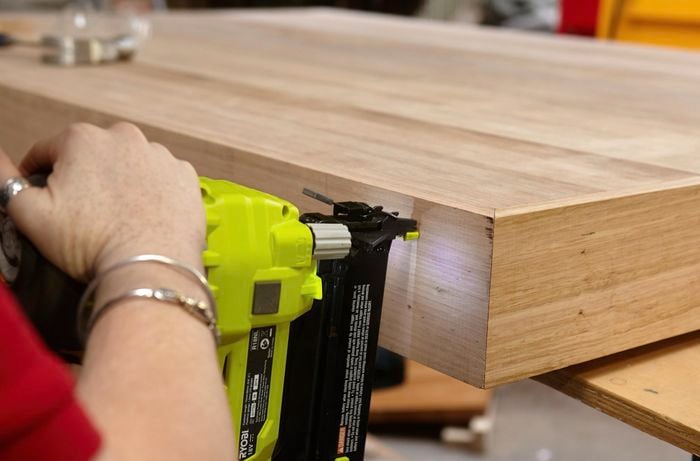 Person securing top of timber bedhead with nail gun.