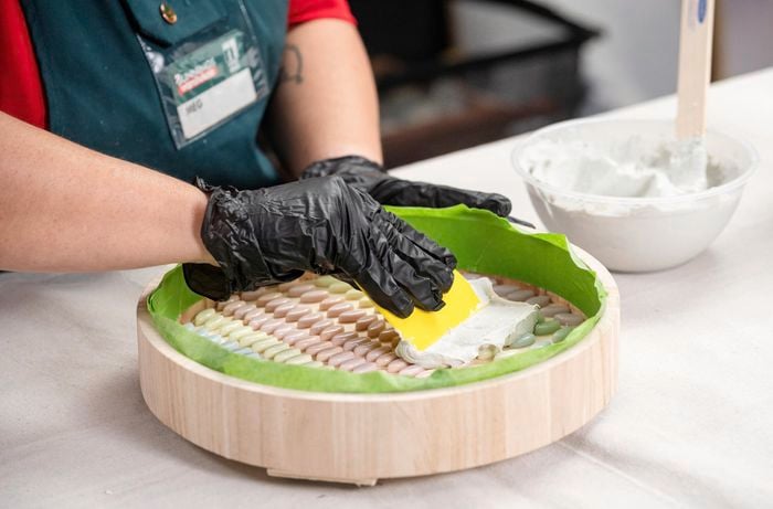 A Bunnings Team Member holding a scarper against a top of a side table