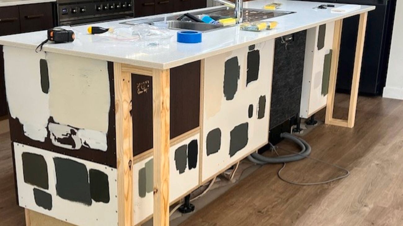 A kitchen bench with a sick in it and different shades of paint painted on it.