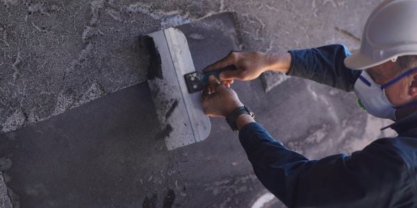 Man applying FIRECOAT to exterior wall.