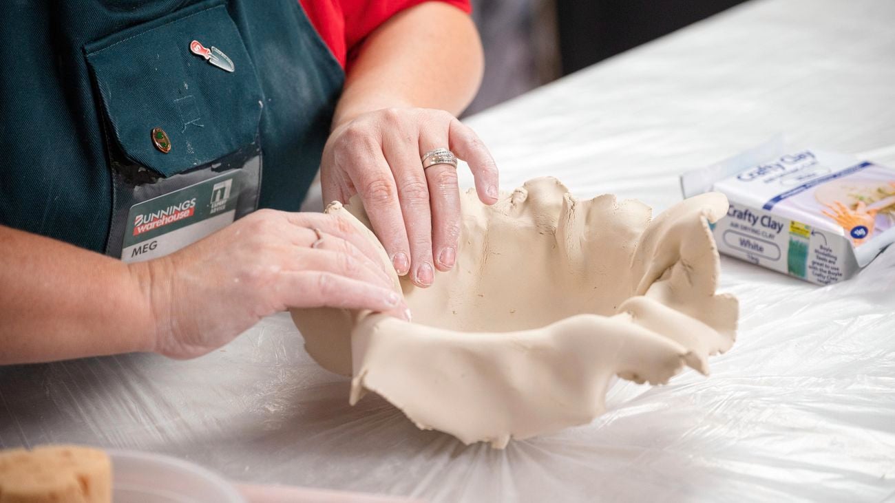 A bunnings team member placing clay into a bowl mould.