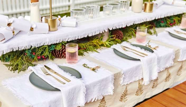 A Christmas table with white bon bons and place settings made from etched pegs and herb sprigs] 