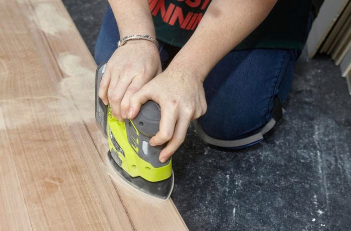 Person using power sander to sand timber bedhead.