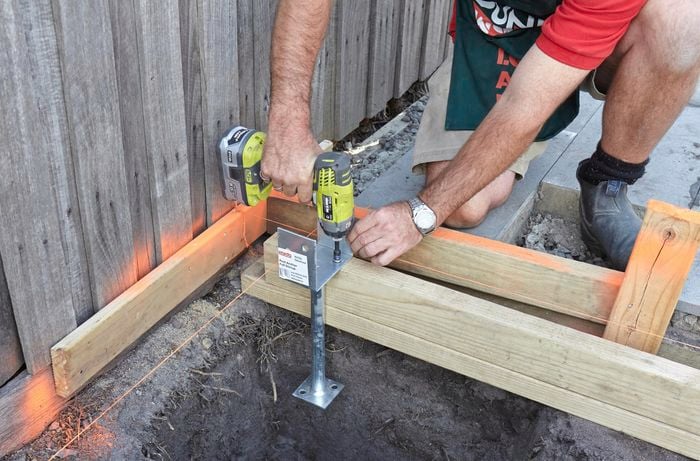 Person screwing a post into piece of timber.