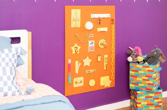 Colourful busy board mounted on a purple wall for fun sensory play