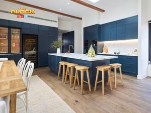 Modern kitchen with navy cabinetry, white island, and wooden stools.