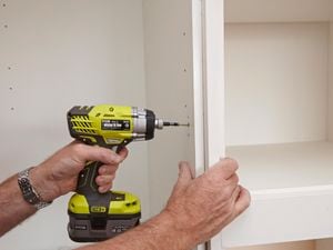 Person attaching two cabinet panels with a cordless driver