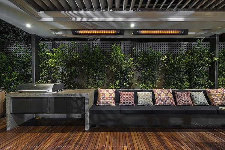 Outdoor entertainment area with couch and plant feature wall heated by wall mounted heat lamps