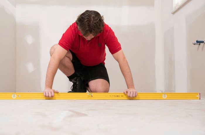 A Bunnings Team Member is using a level surface to check the substrate is as flat as possible before laying sheets.
