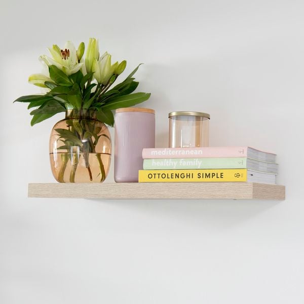 Floating shelf with books, candle and flowers.