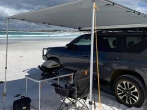 4wd car parked on a beach under a canopy.