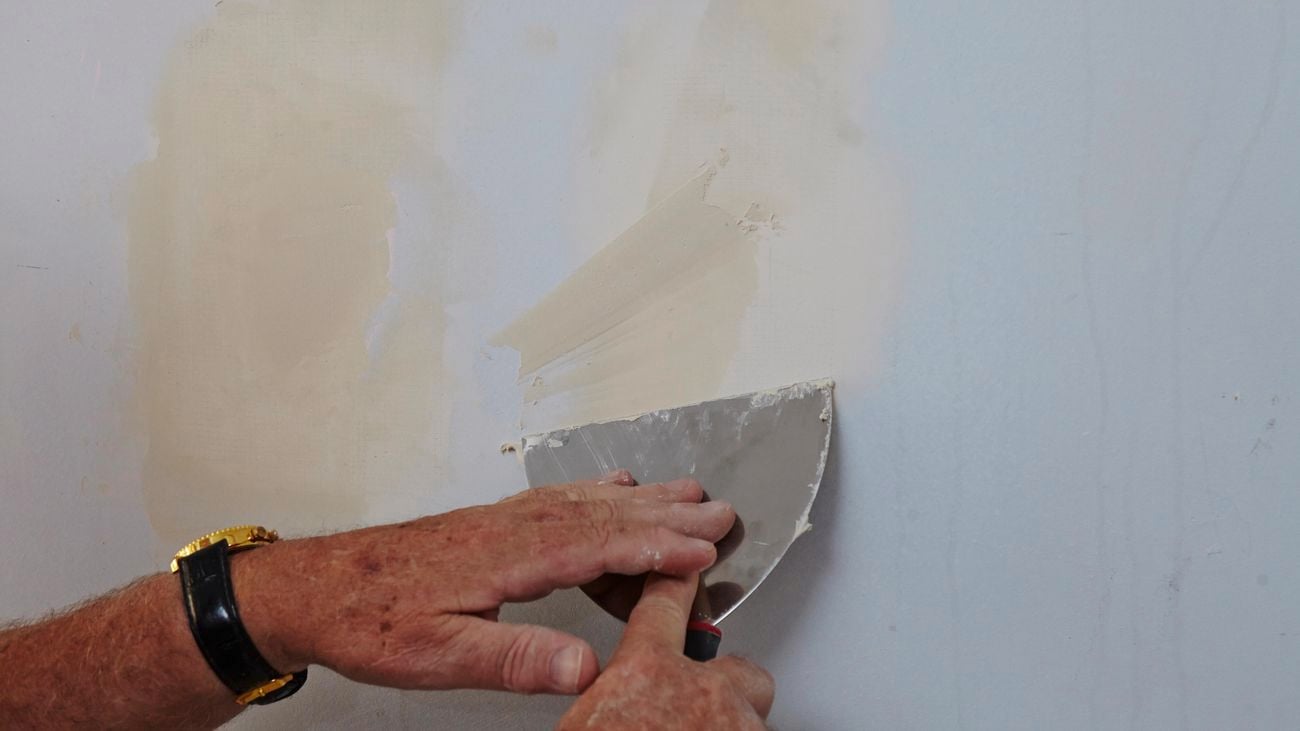 Person patching a hole in a plaster wall