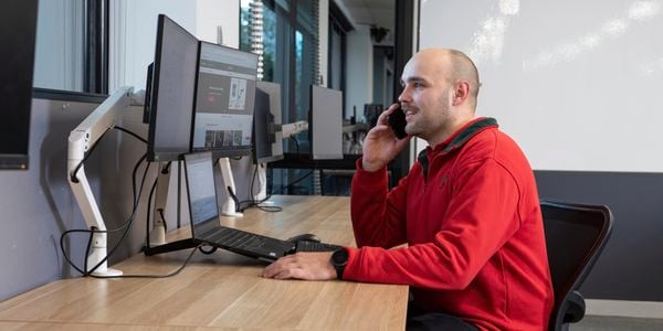 Team member working at call centre looking at website and talking on the phone
