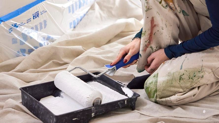 Bella rolling paint in a tray with a roller brush