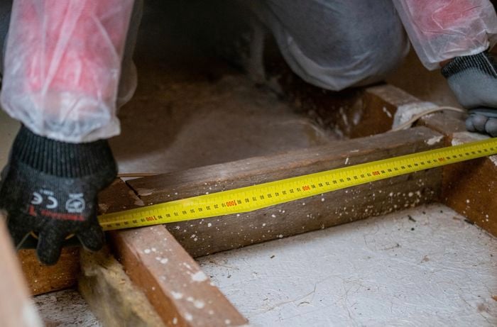 Space between two ceiling joists being measured with a tape measure