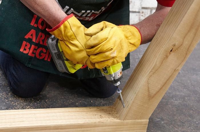 Person drilling screws into two bits of timber.