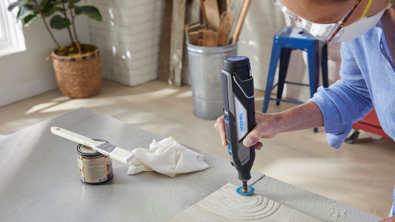 Person using Dremel sanding tool to create shapes in sandstone