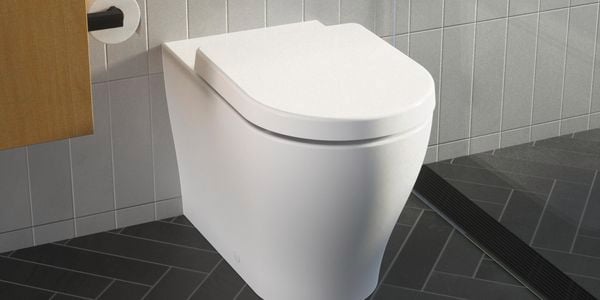 A Caroma wall faced toilet suite with the lid closed, installed in a black and white tiled modern bathroom.