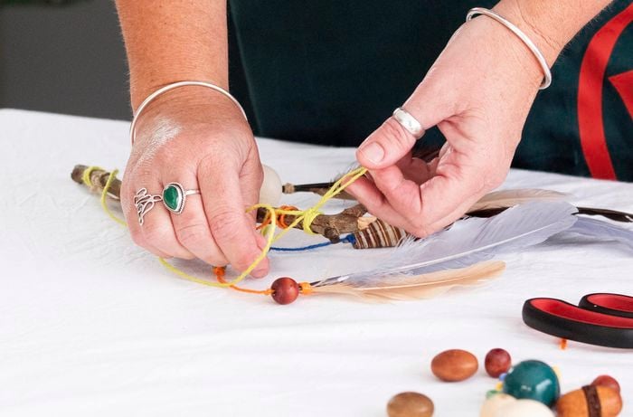 Putting a red bead onto the piece of string.