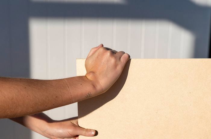 A person is holding a MDF board panel as the base surface to create a simple chalkboard wall.
