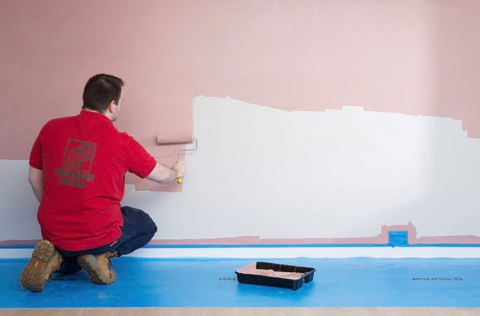 A Bunnings Team Member is painting a wall using a paint roller.