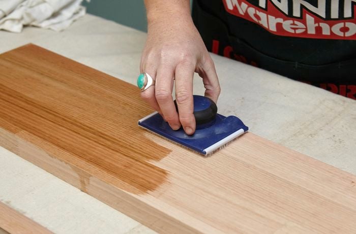 Person varnishing wooden shelf.