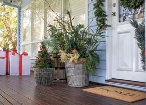 Front door styled with weaved pots with a christmas tree and plants and a home door mat