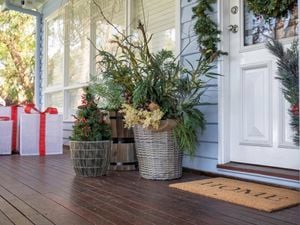 Front door styled with weaved pots with a christmas tree and plants and a home door mat