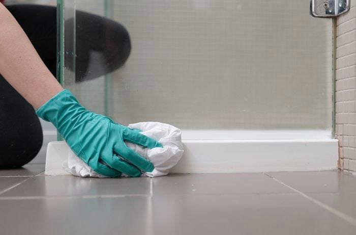 A hand in green gloves is wiping the surface with a cloth.