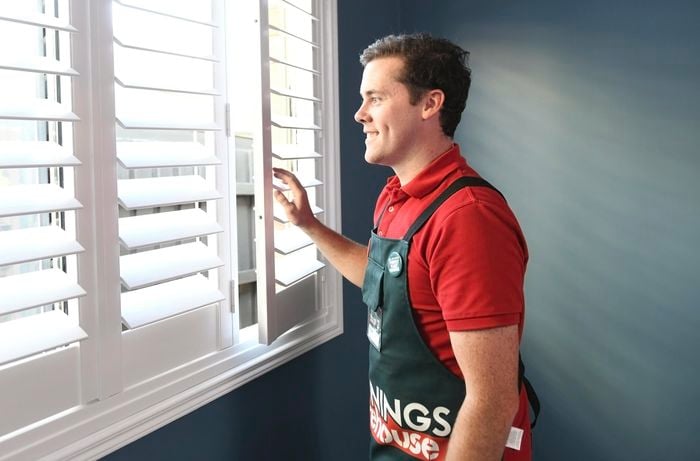 Person looking out a window with plantation shutters