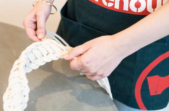 A person measuring a length of cotton rope with their arms at full stretch