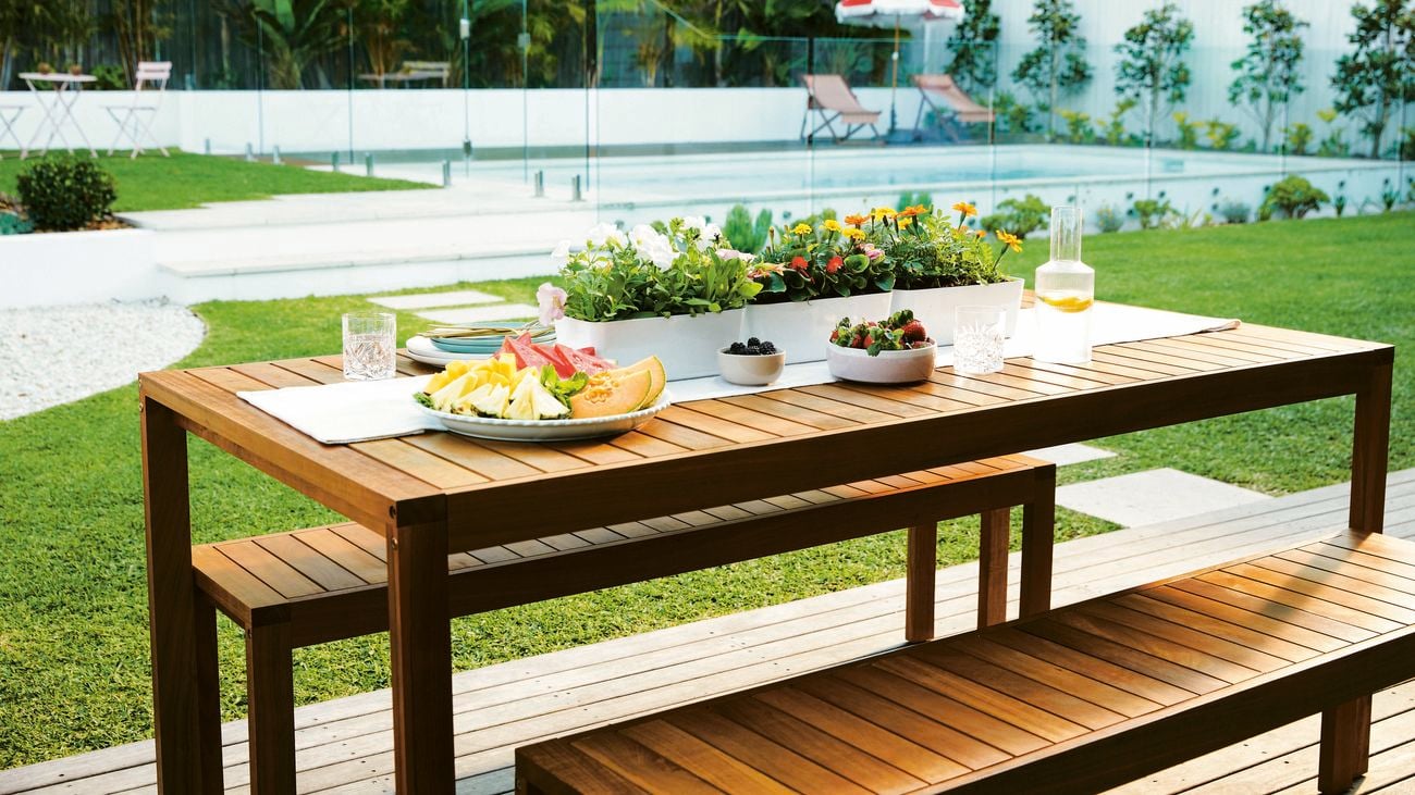 An outdoor table setting decorated with pot plants in a backyard.