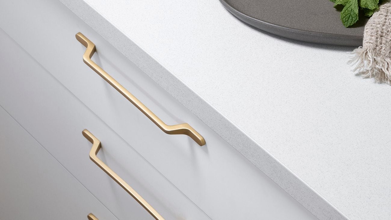 White bench on top of drawers with a grey bar tray with a glass on it.