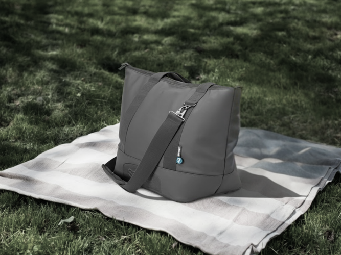 dark grey cooler back sitting on a checked green and white rug
