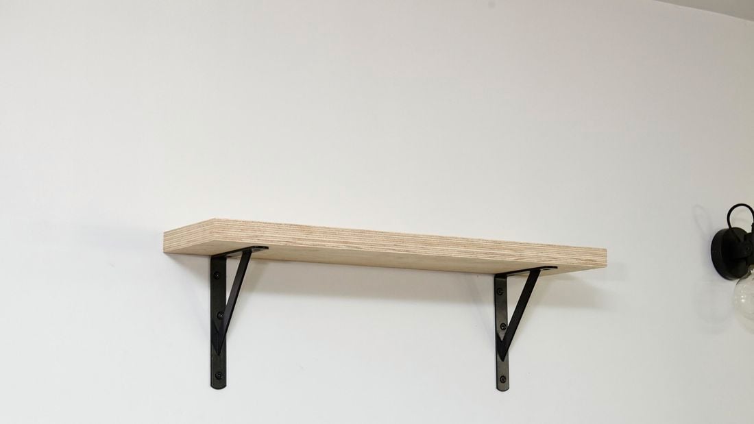 A small timber shelf attached to a wall with black brackets
