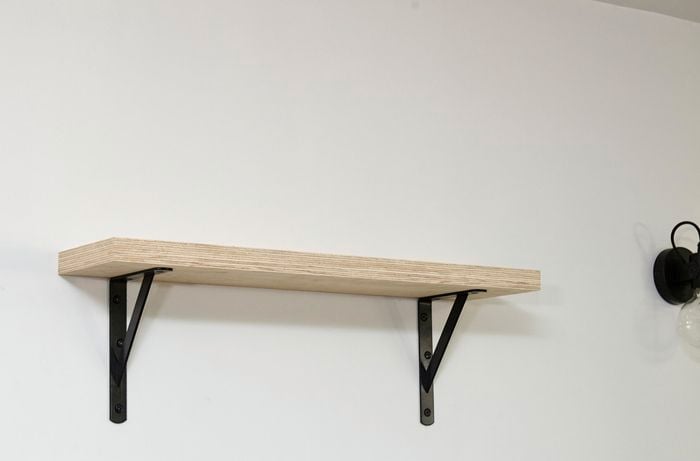 A small timber shelf attached to a wall with black brackets