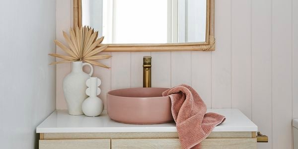 Bathroom with a mirror on the wall above a wooden cabinet with a basin on top of it