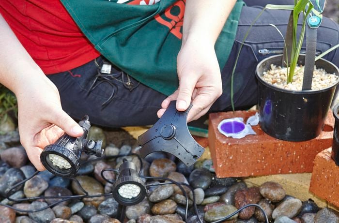 A person holding a pond light and a weighted base
